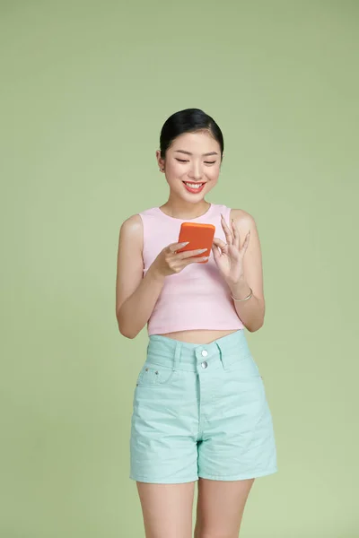 笑迷人的亚洲女人用手机快乐地发短信 与绿色背景隔离 — 图库照片