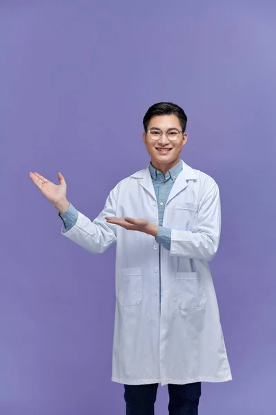 Gülümseyen Genç Erkek Doktor Elleriyle Bir Şey Gösteriyor Sunuyor — Stok fotoğraf
