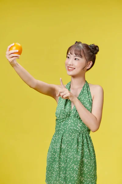 Молодая Азиатка Держит Руках Свежий Апельсин Улыбаясь Счастливо Указывая Рукой — стоковое фото