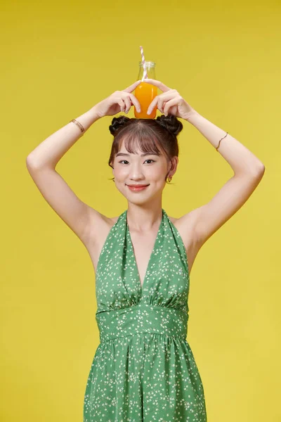 Cute Młoda Dziewczyna Gospodarstwa Sok Pomarańczowy Butelce Szkła Żółtym Tle — Zdjęcie stockowe