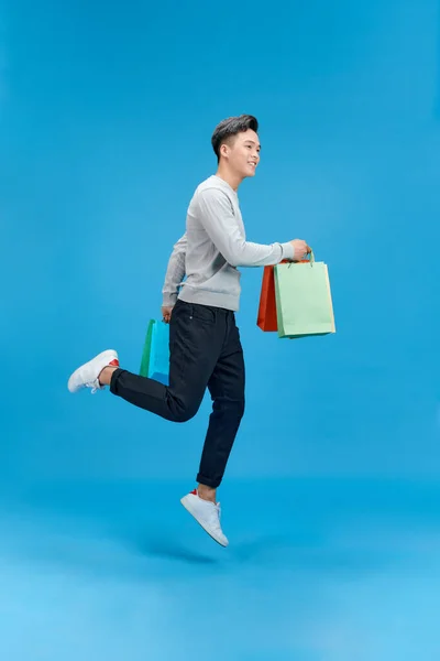 stock image Full size photo of crazy handsome guy hurry rush hold packages jump isolated on blue color background