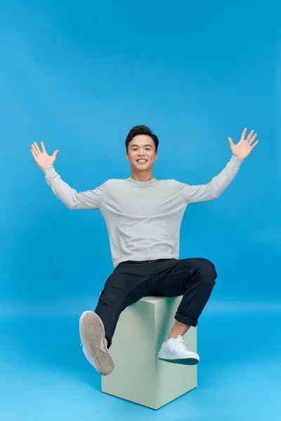 stock image Young Asian person sitting on the cube isolated 