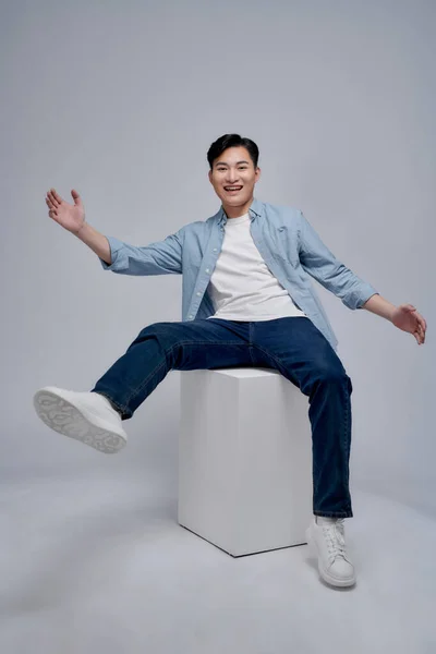 Smiling Happy Asian Man Sitting Cube Studio Background — Stok Foto