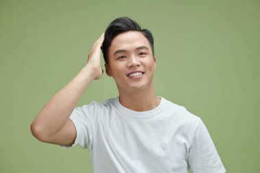 Gülümseyen, kendine güvenen, el hareketleriyle saçlara dokunan çekici ve şık pozlar veren genç bir adam.