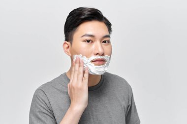 Traş olmadan önce tıraş köpüğü kullanan yakışıklı bir adam.