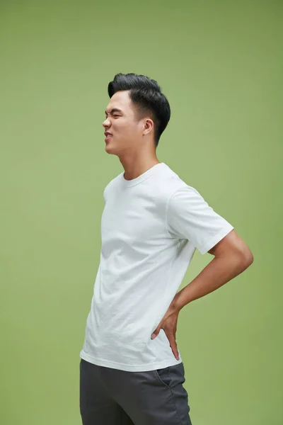 Junger Gutaussehender Mann Isoliert Über Grünem Hintergrund Der Unter Rückenschmerzen — Stockfoto