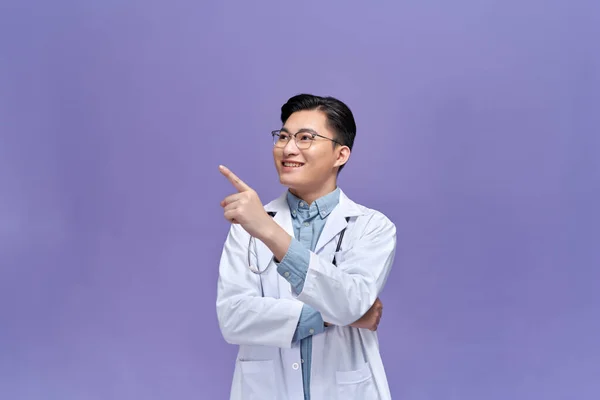 Ung Man Klädd Läkare Uniform Med Ett Leende Ansiktet Pekar — Stockfoto