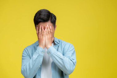 Sarı arka planda yalnız ve çaresiz bir şekilde başını tutan yakışıklı bir adam.