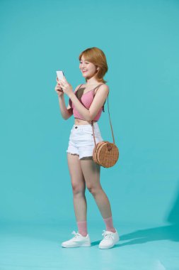 Tam boy profil fotoğrafı mutlu mutlu gülüşler cep telefonu yürüyüşü turkuaz renkli arka plan üzerinde izole edilmiş.