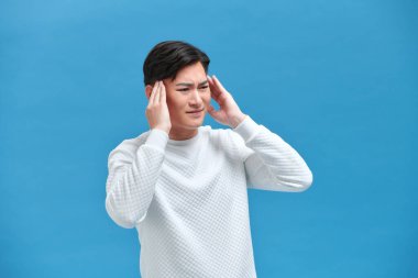 Genç Asyalı adam başını tutarken arka planda başı dönüyor.