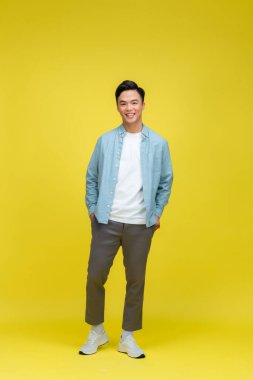 Sarı arka planda poz veren genç Asyalı adam.