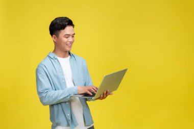 Yetişkin bir Asyalı elinde dizüstü bilgisayarla kameraya bakıyor ve mutlu bir ifade sergiliyor.