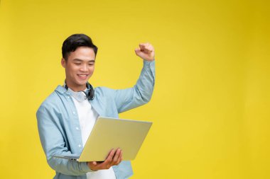 İzole edilmiş sarı arka planda dizüstü bilgisayar kullanan iş adamı