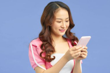 Mavi arka planda izole akıllı telefon kullanan çekici Asyalı kadın.