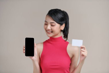 Gülümseyen kadın akıllı telefon uygulamasında plastik kredi kartıyla ödeme yapıyor.