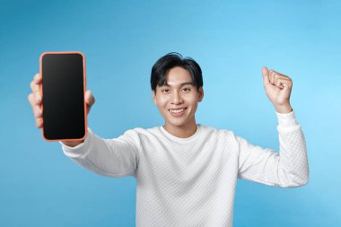 Asyalı yakışıklı genç, uygulamayı göstermek için kocaman bir akıllı telefon modeli tutuyor.,