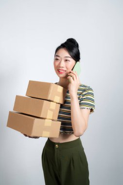 Arka planda telefon ve kutuları olan Asyalı bir kadın.