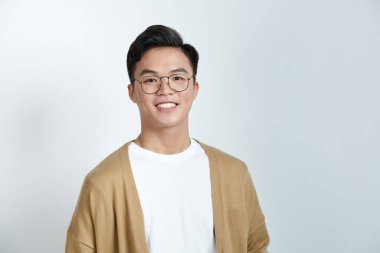 Açık arkaplanda gözlük takan yakışıklı Asyalı genç adamın yakın portresi