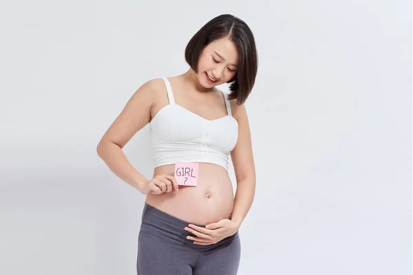 彼女の腹に 疑問符を描いている粘着性のメモを持つ妊婦 — ストック写真