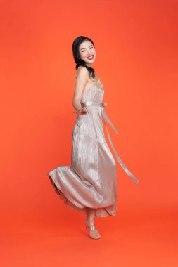 Stüdyoda kırmızı arka planda dans eden parlak elbiseli seksi kız.