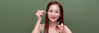 Kırp genç Asyalı kadın yüzüne serum sürüyor, afiş