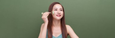 Asyalı kızın panoraması gua sha Jade Quartz silindiri kullanıyor.. 