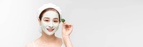 顔に白い栄養マスクと手の緑の葉を持つアジアの女性 隔離された白いバナー — ストック写真