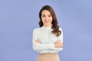 Genç Asyalı kadın izole edilmiş renkli arka planda kollarını önde kavuşturuyor.