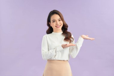 Asyalı kadın gülümsüyor ve bir şey göstermek için ellerini gösteriyor.