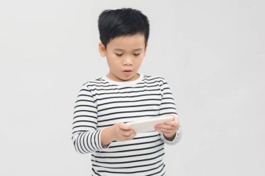 Beyaz afiş üzerine akıllı telefon kullanan ciddi küçük çocuk..