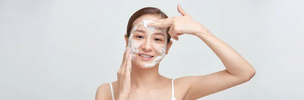 在护肤过程中 用泡沫擦拭脸部时 让快乐的年轻女人微笑着收割 — 图库照片