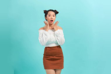 Güzel kız, açık mavi arka planda izole edilmiş bir şey söyler gibi davranır.