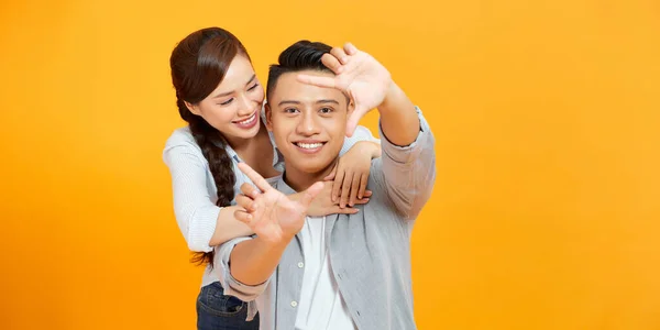 Photo of happy creative trendy couple show camera frame fingers isolated on yellow background