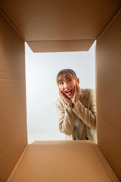 young woman feels overjoyed getting long-awaited parcel with goods smile, view from bottom of box.