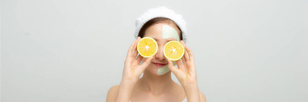 Smiling woman with orange slices and mud mask on face for web banner