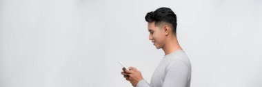 Beyaz arka planda izole edilmiş cep telefonu kullanan gülümseyen genç adam görüntüsü