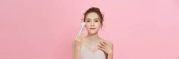 年轻女子用化妆品刷在脸上涂粉 — 图库照片