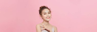 Omzunun üzerinde pembe bir arka planda parıldayan derisi olan model bir kız.