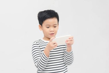 Beyaz afiş üzerine akıllı telefon kullanan ciddi küçük çocuk..