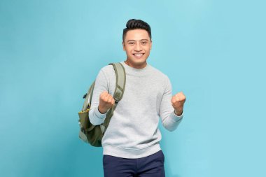 Mutlu Asyalı genç turist portresi. Turist sırt çantalı. Yumruklarını kaldırarak başarılı bir jest yapıyor.