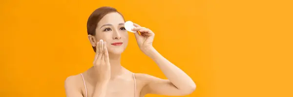 Asian young woman using cosmetic pad or cotton pad remove makeup cares for face skin, banner.