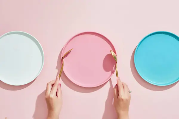 Restaurant and Food theme: the human hands  and empty three color plates on a pink background