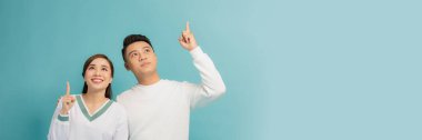 Mutlu çift mavi arka planda bir şeye işaret ediyor.