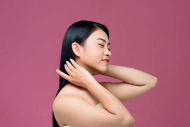 Çekici, tatlı bir kadın uzun saçlarının kalitesinin keyfini çıkarırken dikilip başka tarafa bakıyor.