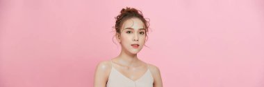 A smiling attractive woman in summer dress posing isolated over pink background