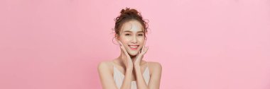 Omzunun üzerinde pembe bir arka planda parıldayan derisi olan model bir kız.