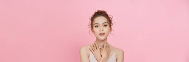  beauty Asian woman with beauty makeup showing fresh and clean skin isolated on pink background