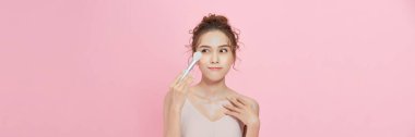 Woman applies powder on the face using makeup brush. 