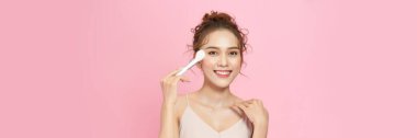 Closeup portrait of beautiful happy young girl with perfect skin is holding makeup brush in hand.