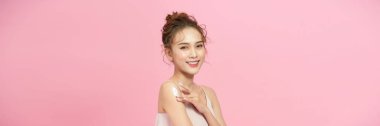 Gorgeous girl with soft makeup applying moisturizing skincare cream on shoulder